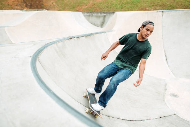 skateboard asiatico maschile in uno skate park - extreme skateboarding action balance motion foto e immagini stock