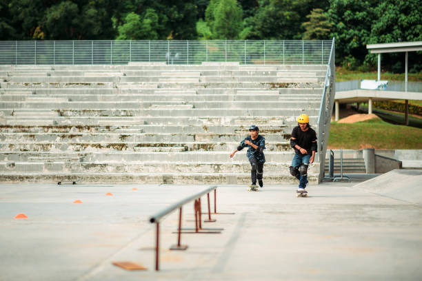 due maschi asiatici che pattinano in uno skate park - extreme skateboarding action balance motion foto e immagini stock