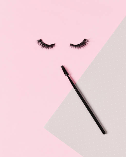 istock Creative layout with eyelashes and brush mascara. Closed eyes on pastel pink background. 1318140466