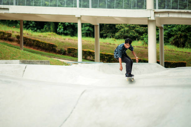 skateboard asiatico maschile in uno skate park - extreme skateboarding action balance motion foto e immagini stock