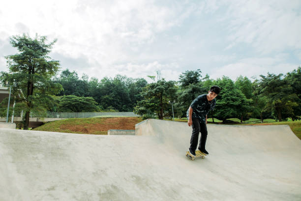 skateboard asiatico maschile in uno skate park - extreme skateboarding action balance motion foto e immagini stock