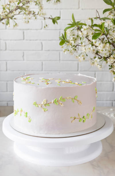Wedding pink cake cake on a stand among branches of cherry blossoms. delicate decor on cake