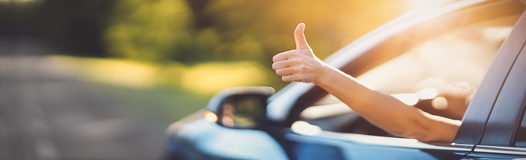 Woman inside her car gesticulate thumb up. Concept of buying car and positive emotion.