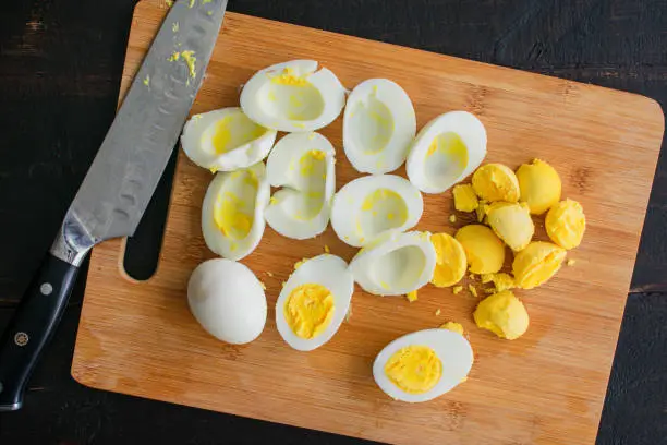 Hard-boiled eggs and yolks on a bamboo cutting board