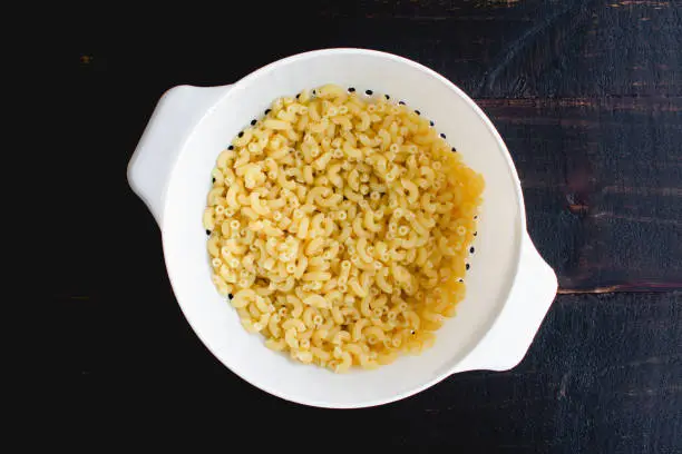 Drained macaroni pasta in a plastic colander