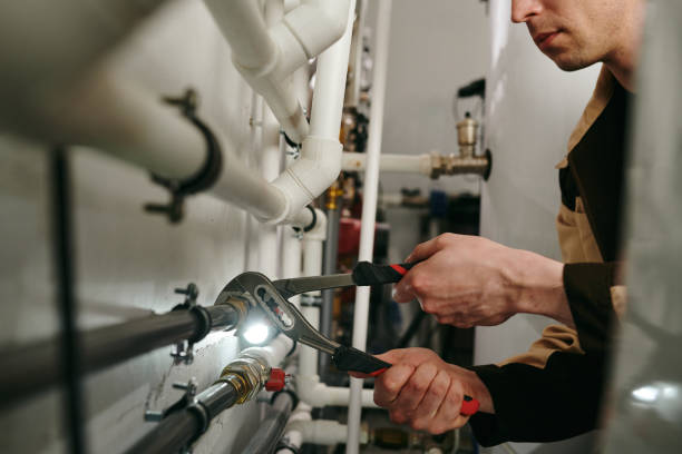 un homme utilisant un outil pour fixer des parties des pipes pendant le travail - plumber photos et images de collection