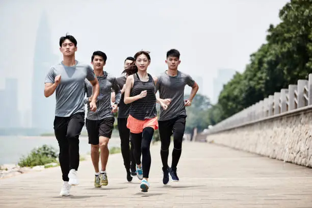 Photo of group of young asian adults running outdoors