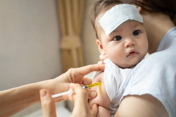 istock asian baby infant get fever and apply cool patch on forehead getting injection for vaccination on arm by doctor. cold pad gel healing temperature. baby sick and crying. 1318154672