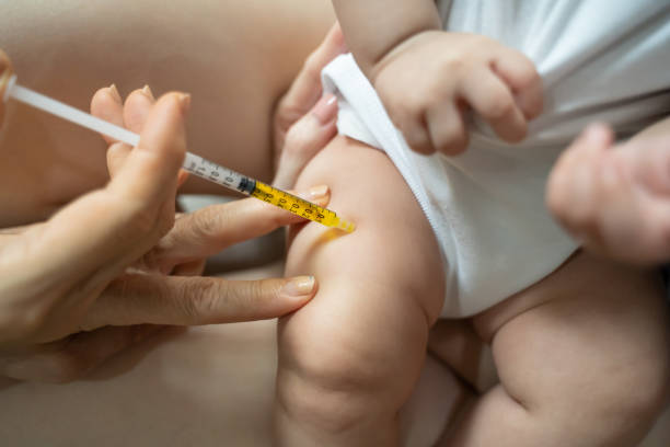 istock asian baby infant get fever and apply cool patch on forehead getting injection for vaccination on leg by doctor. cold pad gel healing temperature. baby sick and crying. 1318154676