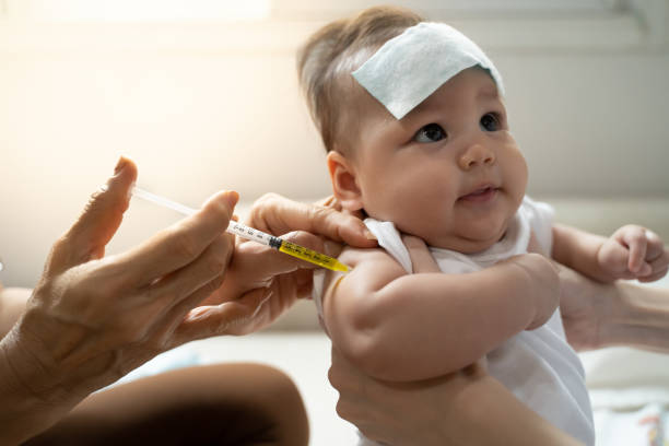 istock asian baby infant get fever and apply cool patch on forehead getting injection for vaccination on arm by doctor. cold pad gel healing temperature. baby sick and crying. 1318154683