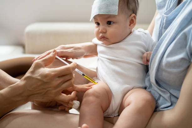 istock asian baby infant get fever and apply cool patch on forehead getting injection for vaccination on leg by doctor. cold pad gel healing temperature. baby sick and crying. 1318154701