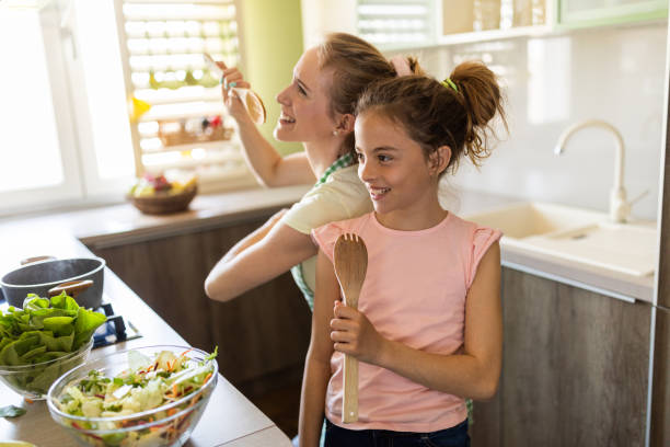 istock Happy mother and daughter having fun while singing in the kitchen 1318157466