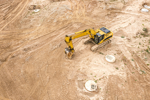 yellow industrial excavator working on construction site. drone point view
