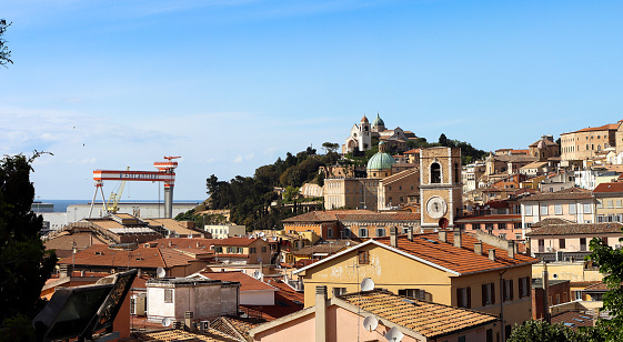 Ancona, Italy - May 15, 2021: Panorama of the city of Ancona with a view of its Cathedral, on the left you can see the crane of the Fincantieri owned by the Cantieri navali di Ancona. The cathedral of Ancona is dedicated to San Ciriaco and is the metropolitan cathedral of the archdiocese of Ancona-Osimo. It is a medieval church where the Romanesque style blends with the Byzantine one, evident in the plan and in many decorations.