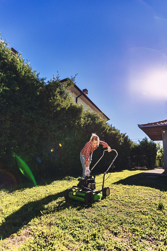 Mid women using a lawn mower in her backyard