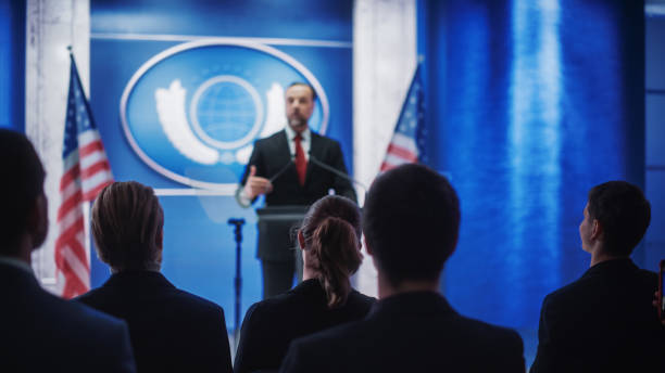 istock Inspiring Organization Representative Speaking at a Press Conference in Government Building. Press Officer Delivering a Speech at a Summit. Minister at Congress. Focus on Public. 1318165793