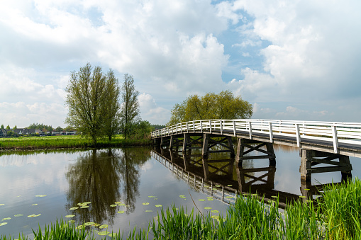 white wooden bridge across a calm canal in country landscape in South Holland