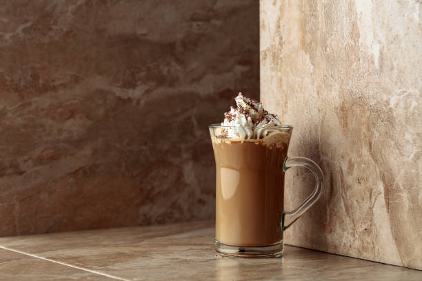 istock Glass cup of coffee latte on a beige ceramic table. 1318169774