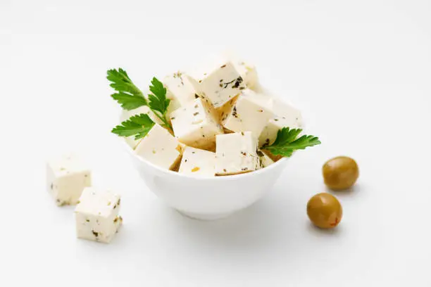 Bowl of diced soft feta cheese on white background