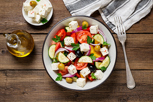 Classic Greek salad with fresh vegetables, feta cheese and olives. Healthy food. Wooden background. Top view