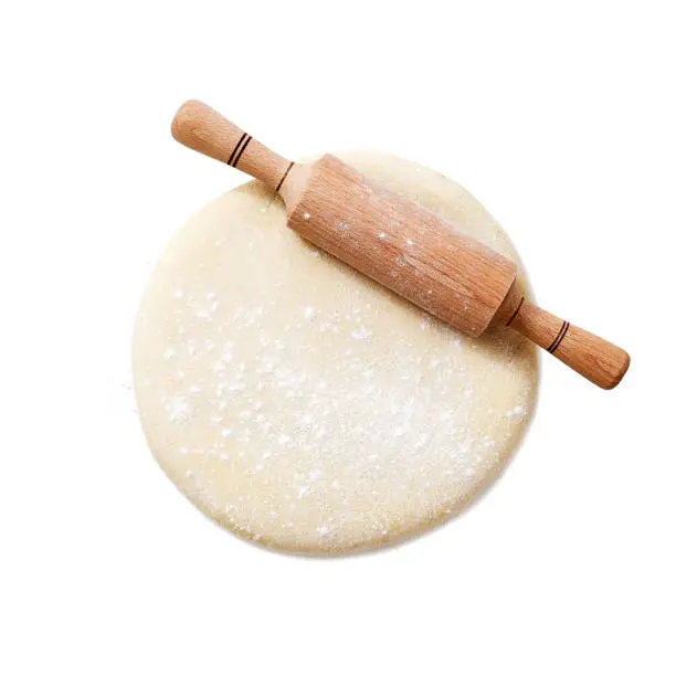 Rolling pin with dough isolated on white background. top view