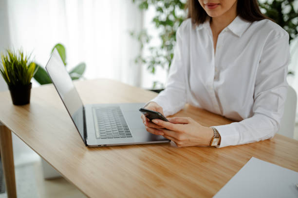 istock Businesswoman using mobile phone and writing a message while sitting on the table in office. 1318174296