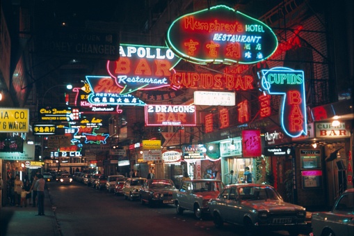 British Hong Kong, China, 1971. Portland Street with its neon signs, bars, nightclubs, shops and restaurants in the Hong Kong red light district. Also: pedestrians and cars.