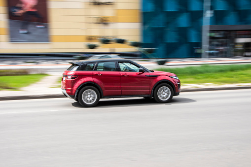 A red SUV driving in the city center. All items in the scene are 3D, concept car is not based on any real vehicles