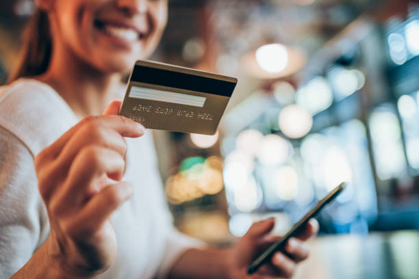 donna che usa smartphone e carta di credito per lo shopping online nel caffè della città. - carta di credito foto e immagini stock