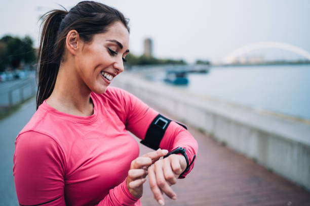 jeune femme sportive vérifiant l’heure après jogging. - checking the time watch women looking photos et images de collection