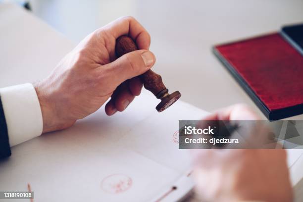 Closeup Of A Persons Hand Stamping With Approved Stamp On Certificate Or Other Document Stock Photo - Download Image Now