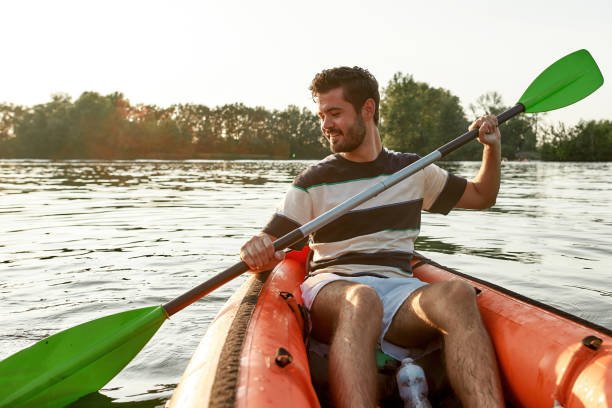 istock Excited young man smiling while kayaking in a lake, surrounded by peaceful nature scene on a summer afternoon 1318192116