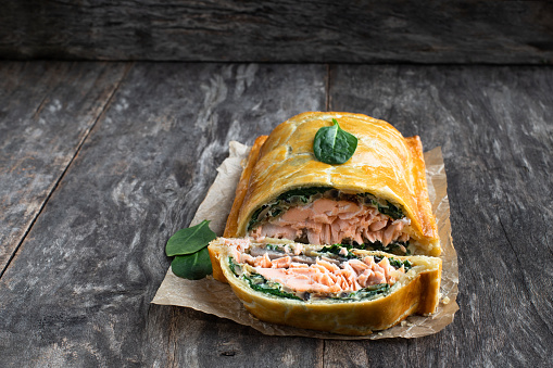 Homemade  salmon wellington with spinach and mushrooms on rustic wooden table