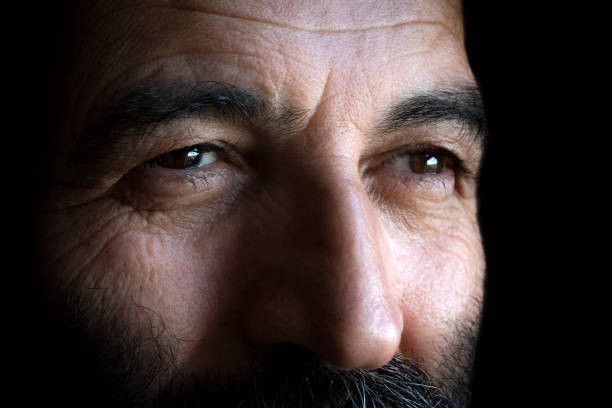 A portrait of 50-55 years old Turkish mature man. The photo was isolated with black background. This photo was taken indoors in front of the window with daylight.