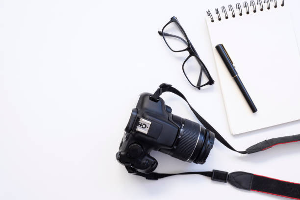 istock top view of work space photographer with digital camera, lens, blank notebook, pencil, glasses, camera accessory on white table background 1318200322