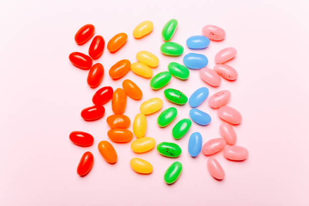 Sweet rainbow jelly beans on pink background. Top view Sweet rainbow jelly beans on pink background. candy jellybean variation color image stock pictures, royalty-free photos & images