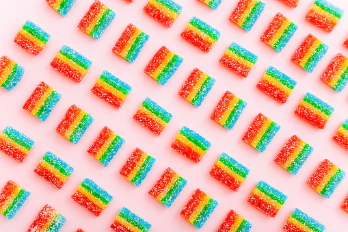 Rainbow juicy gummy candies background. Pattern from jelly sweets on pink background. Top view