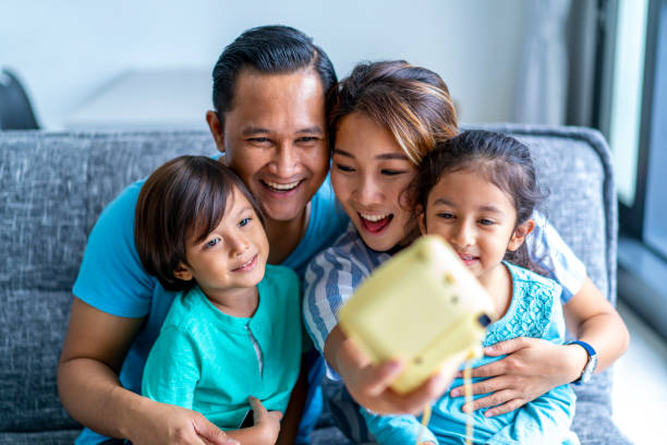 junge mixed rasse asiatische familie bindung zu hause mit einer polaroid-kamera. - polaroid transfer fotos stock-fotos und bilder
