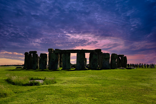 Close-up view of ancient stones during sunset at UNESCO World Heritage Site at Stonehenge, Wiltshire, UK. Sun shines through the stones. Major tourist destination, archeological and pilgrimage site during Summer Solstice and Winter Solstice. Visible grain, softer focus.