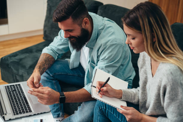 istock Young beautiful couple using a laptop calculating their finances at home 1318204714