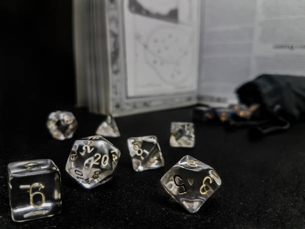 Set of transparent dice. Set of transparent dice for role play, placed on a black surface, with a manual and a bag of dice in the background. developing 8 stock pictures, royalty-free photos & images