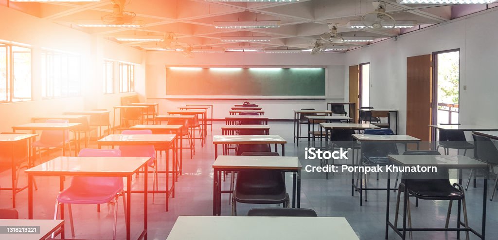 School classroom in blur background without young student; Blurry view of elementary class room no kid or teacher with chairs and tables in campus. Classroom Stock Photo