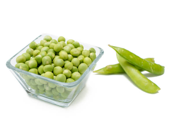 istock Peeled peas in a glass container with some peas in the shell on one side on a white background 1318223114