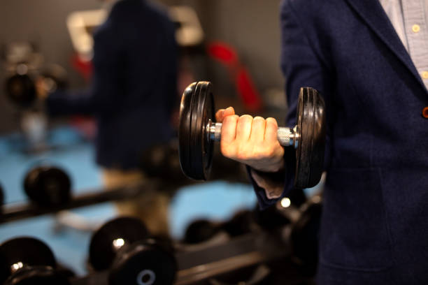 Businessman in a suit is training with dumbbell. Concept: business training. Effort is required to achieve results.