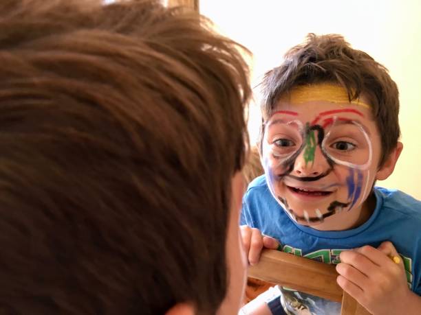 istock Child with Face Paint looks in Mirror 1318234514