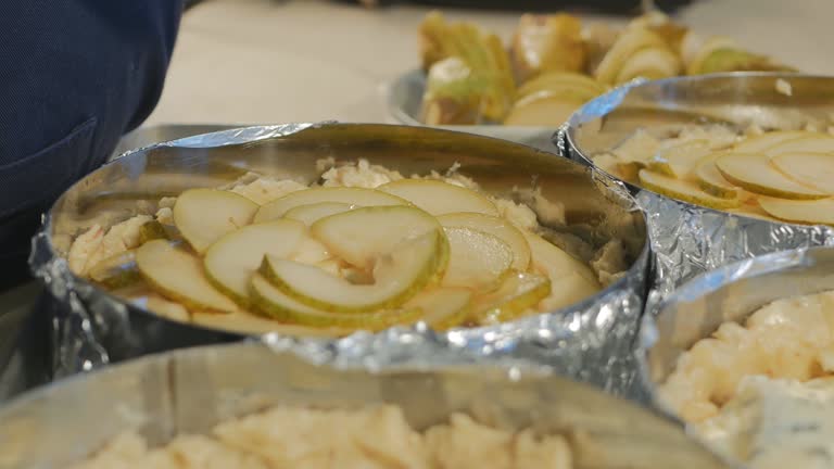 a pastry chef in black rubber gloves puts pieces of ripe pears on the cake blanks. Shortcrust pastry, cream, cheese and pear pie. Delicious dessert