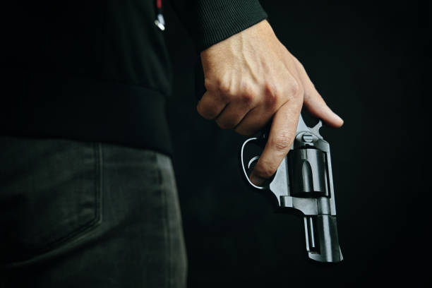 istock Man in dark clothing is holding gun. 1318241432