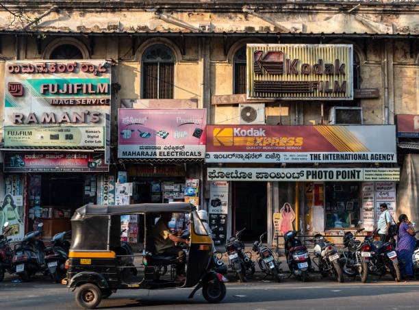 an auto rickshaw rides past vintage shop signs - eastman kodak company imagens e fotografias de stock