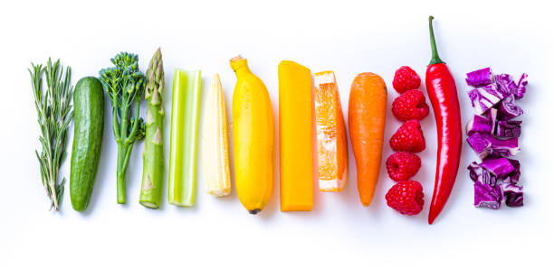 Rainbow colored fruits and vegetables sticks on white background