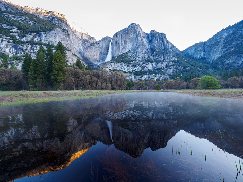 Yosemite National Park - Reflection in Merced River of Yosemite waterfalls at sunrise